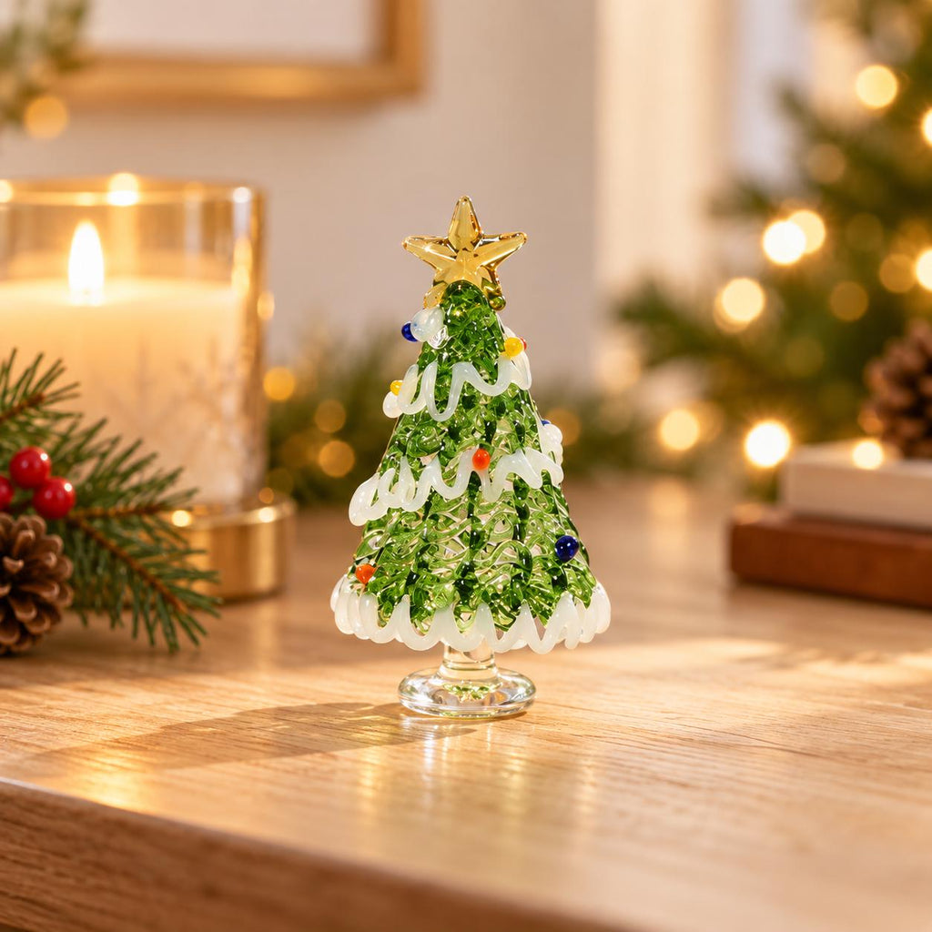 May include: A miniature glass Christmas tree figurine featuring a textured green body, a clear glass base, and a gold-colored star topper. The tree is decorated with white glass garland swirls and small, multi-colored glass spheres.