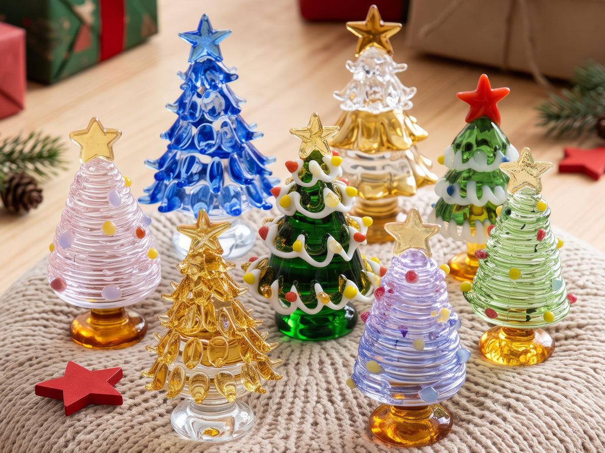 May include: A collection of eight miniature glass Christmas tree figurines in various colors including blue, gold, green, pink, and light purple. Each tree features a star topper and decorative glass accents, standing on a circular base.