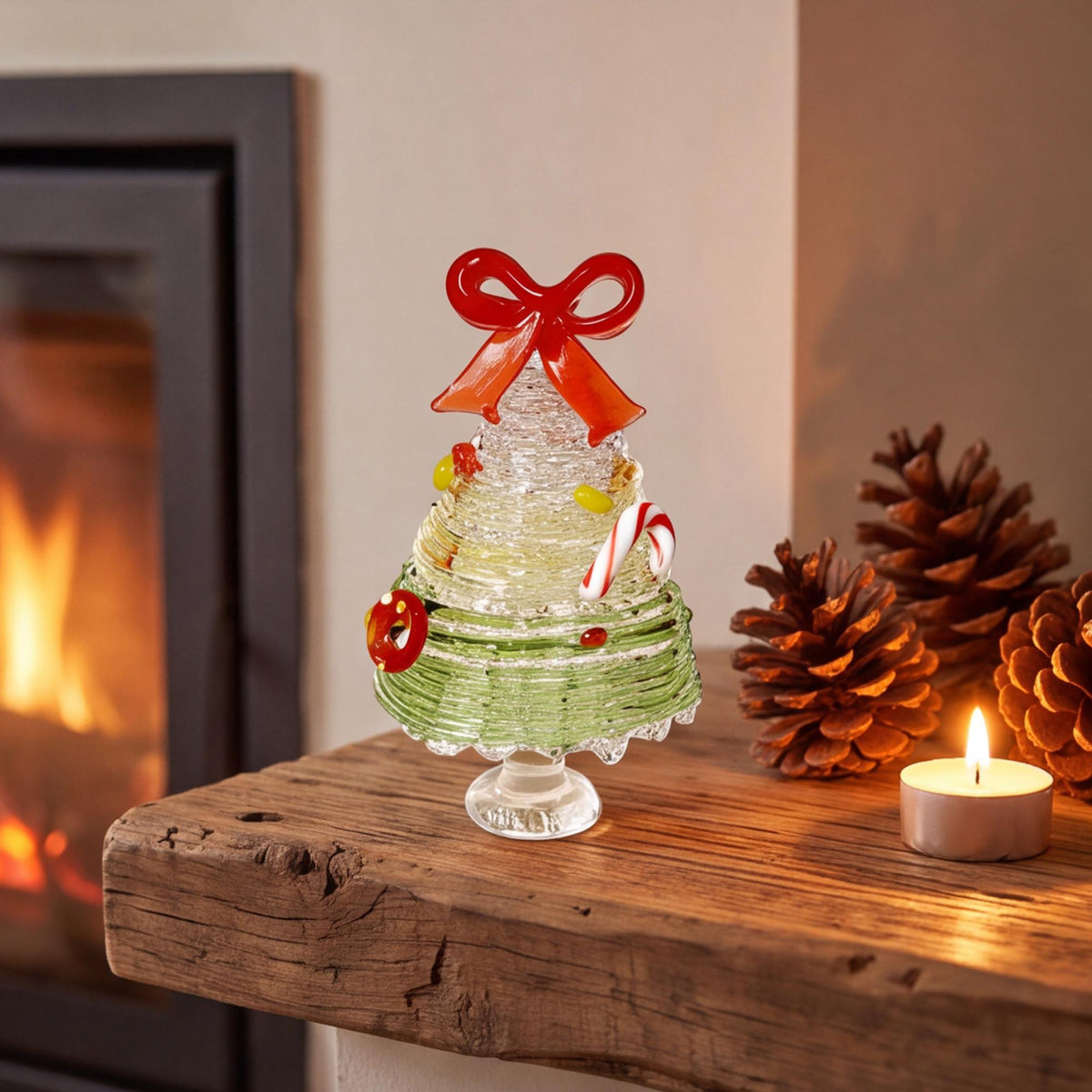 May include: A glass Christmas tree figurine featuring a textured, layered design in shades of light green and clear glass. The tree is topped with a bright red glass bow and decorated with small glass candy canes and circular ornaments.