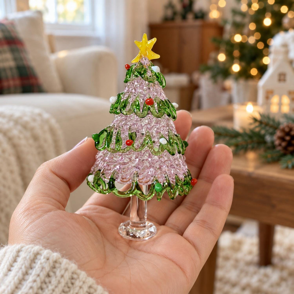 May include: A miniature glass Christmas tree ornament featuring a textured light pink body with swirling green glass branches, small red and white glass bead accents, and a bright yellow glass star topper, supported by a clear glass pedestal base.
