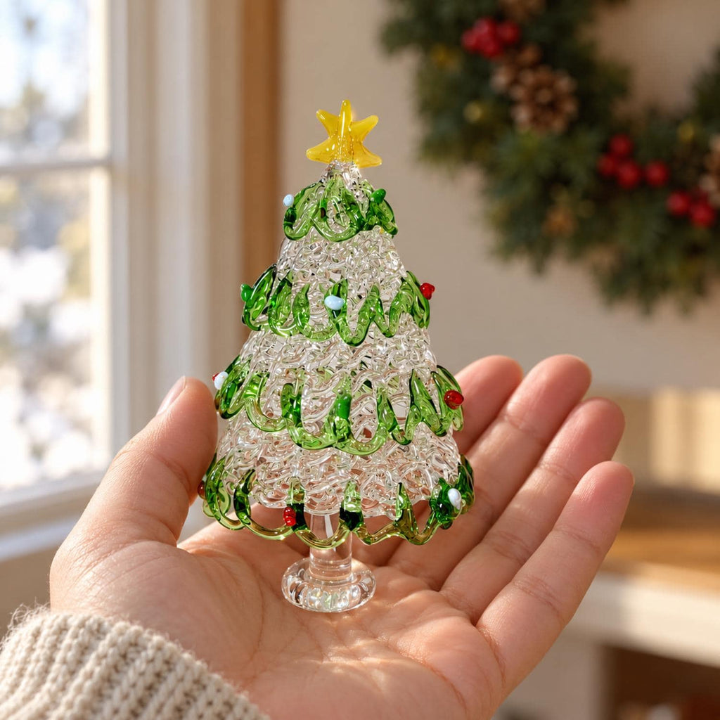 May include: A small, clear glass Christmas tree figurine featuring a textured, crystalline body wrapped in a spiraling green glass garland. The tree is topped with a bright yellow glass star and accented with tiny red and white glass beads.