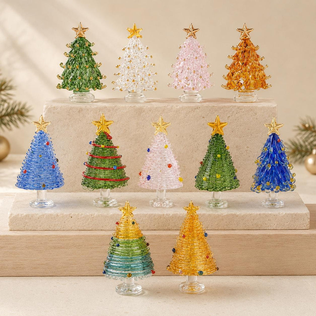 May include: A collection of eleven miniature glass Christmas trees in various colors including green, clear, pink, amber, blue, and multi-colored designs. Each tree features a gold star topper and a clear glass base, arranged on tiered stone blocks.