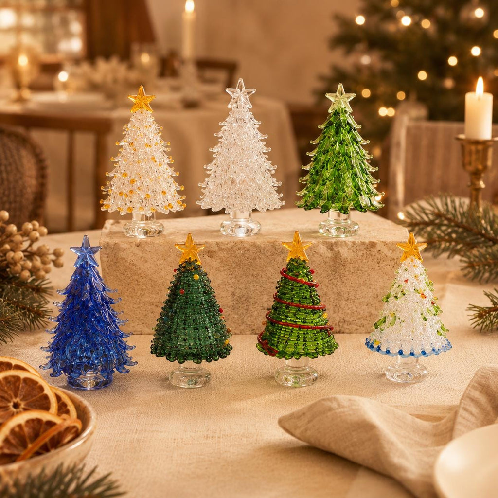 May include: A collection of seven miniature glass Christmas trees in various colors including clear, gold, green, blue, and white. Each tree features a textured, branch-like design and is topped with a small star, standing on a clear glass base.