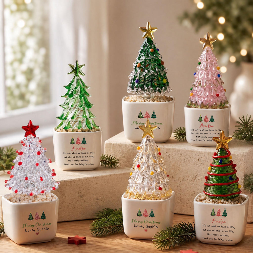 May include: Six glass Christmas tree ornaments in white ceramic pots. Each tree features a star topper and colorful accents. The pots are printed with 'Merry Christmas', 'Love, Sophia' or 'Amelia', and a quote about life and gratitude.