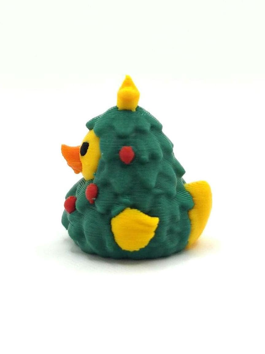 May include: A small rubber duck figurine shaped like a Christmas tree. The duck has a yellow head, a bright orange beak, and a dark green body textured like pine needles. Small red dots decorate the green surface, and a yellow star sits on top.