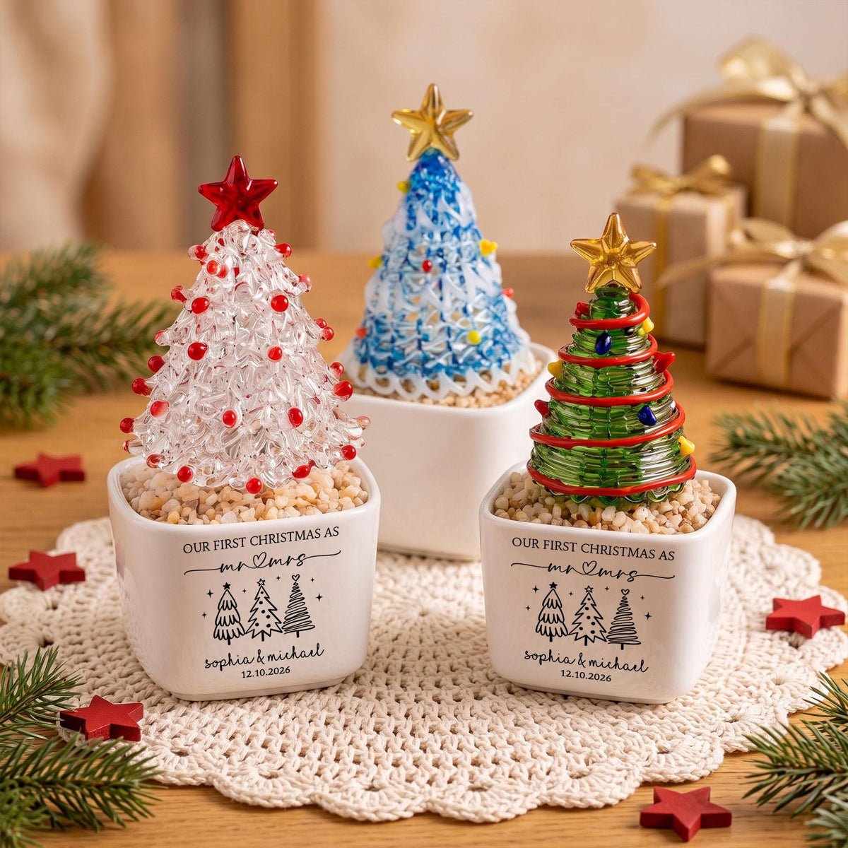 May include: Three glass Christmas tree ornaments in white square planters. Each tree features a star topper and colorful accents. The planters are printed with the text "OUR FIRST CHRISTMAS AS mr & mrs", "Sophia & Michael", and "12.10.2026".