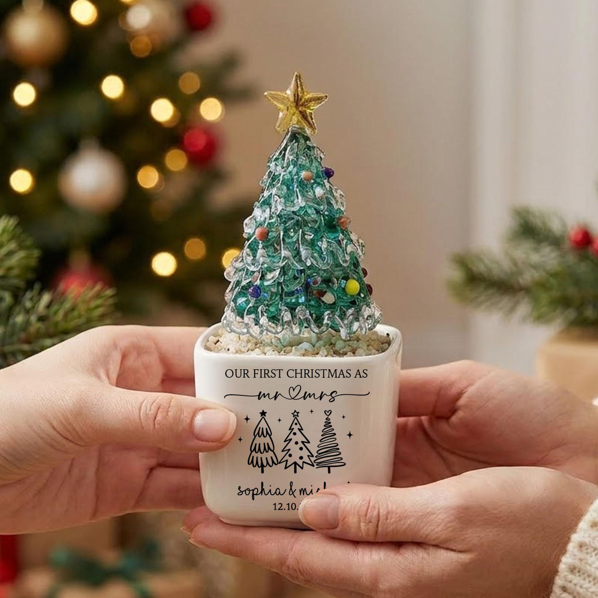May include: A glass Christmas tree ornament with a gold star topper and colorful glass beads, set in a white ceramic pot. The pot features black text reading "OUR FIRST CHRISTMAS AS mr & mrs", "sophia & michael", and "12.10."