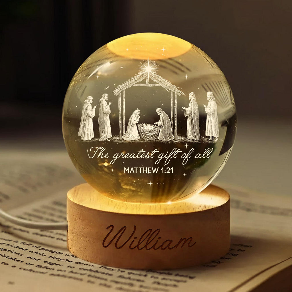 May include: A clear glass sphere night light featuring an internal laser-etched nativity scene with figures, a stable, and the text "The greatest gift of all MATTHEW 1:21". The sphere rests on a round wooden base engraved with the name "William".