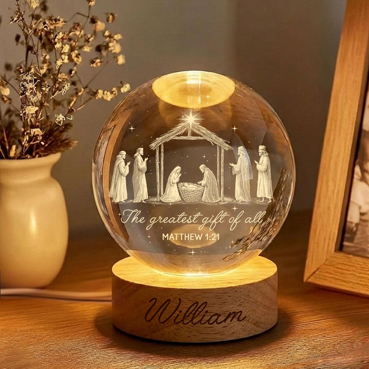 May include: A clear glass sphere lamp featuring an internal 3D laser-etched nativity scene with figures, a stable, and the text "The greatest gift of all MATTHEW 1:21". The sphere rests on a round wooden base with the name "William" engraved on it.
