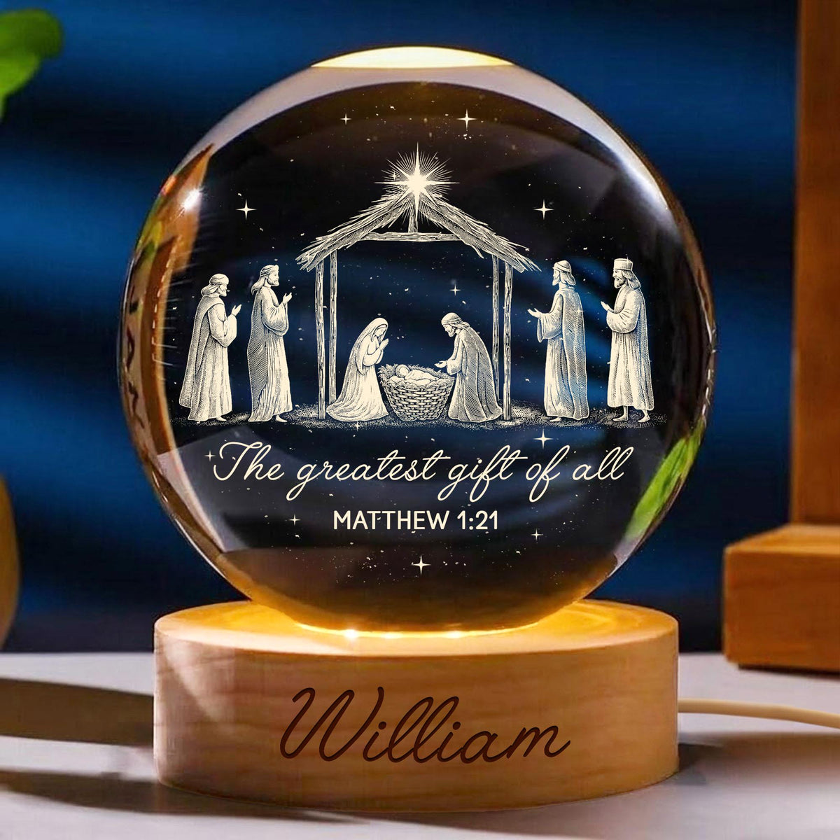 May include: A clear glass sphere night light featuring a laser-etched nativity scene with figures, a stable, and a star. The text reads, "The greatest gift of all" and "MATTHEW 1:21". The sphere rests on a round wooden base engraved with the name "William".