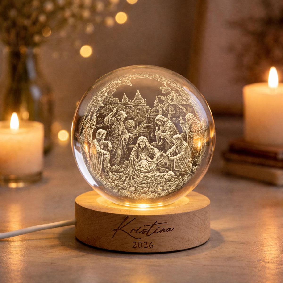 May include: A clear glass sphere featuring an intricate 3D laser-engraved nativity scene with figures surrounding a central infant. The sphere rests on a round wooden base engraved with the name Kristina and the year 2026, illuminated from below.