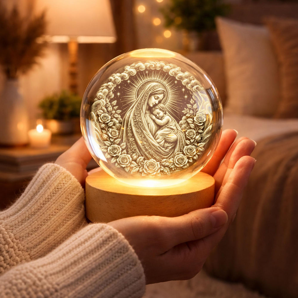 May include: A clear glass sphere featuring an internal 3D laser-etched engraving of the Virgin Mary holding the infant Jesus, surrounded by a circular wreath of roses and clouds, mounted on a circular light-up wooden base.