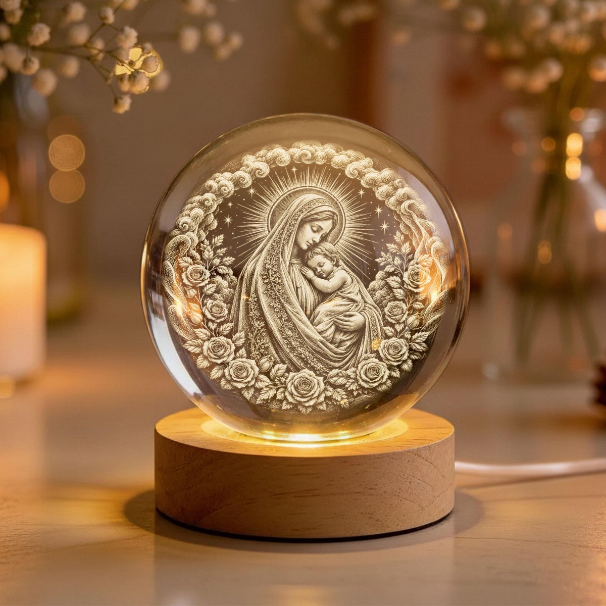 May include: A clear glass sphere featuring an intricate 3D laser-etched engraving of a mother holding a child, surrounded by a circular wreath of roses and clouds. The sphere rests on a cylindrical light-colored wooden base with an internal light.