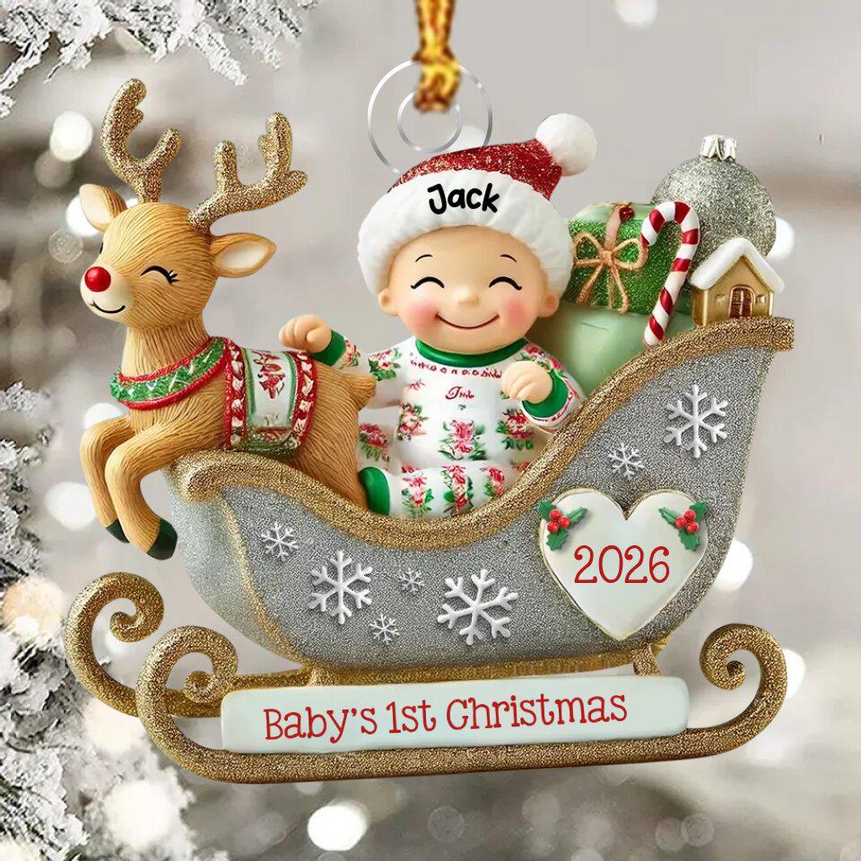 May include: A Christmas ornament featuring a baby wearing a red and white hat labeled Jack, sitting in a silver glittery sleigh with a reindeer. The sleigh displays the text Baby's 1st Christmas and a heart with 2026. It includes gifts and a candy cane.