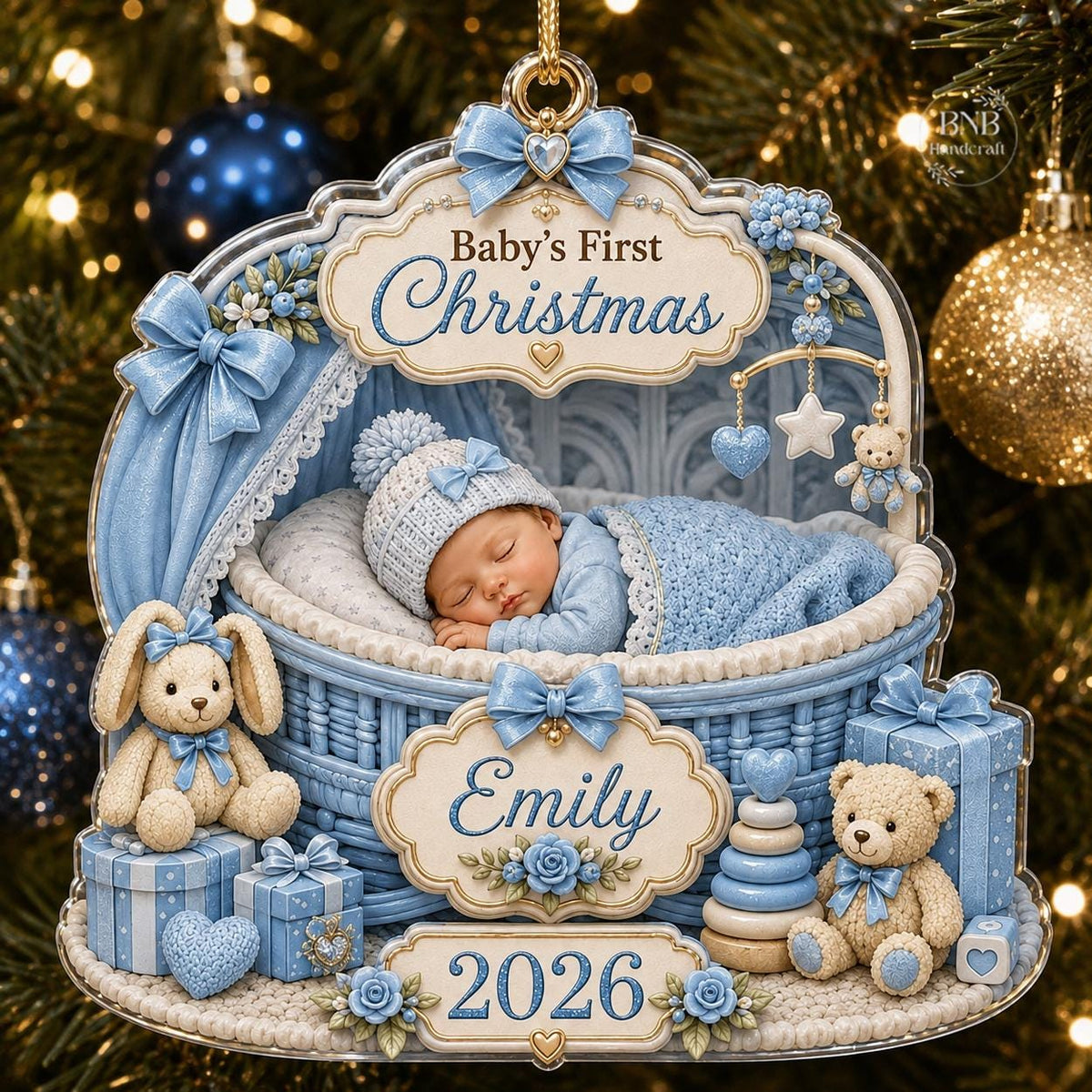 May include: A decorative ornament featuring a sleeping baby in a blue wicker cradle. The text reads Baby's First Christmas, Emily, and 2026. It includes a blue knitted hat, a blue blanket, two teddy bears, gift boxes, and a mobile with stars.