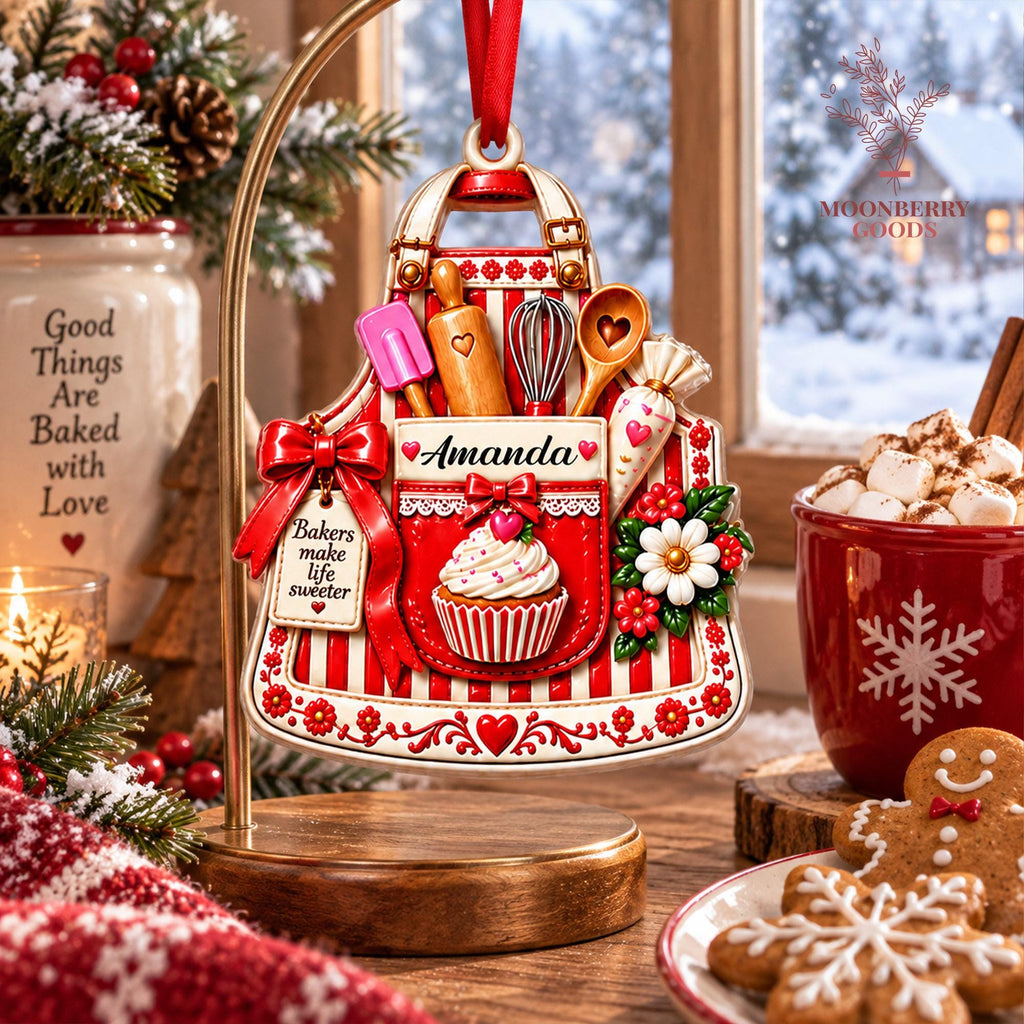May include: A red and white striped apron-shaped Christmas ornament featuring a pocket with the name Amanda, a cupcake graphic, and baking tools including a spatula, rolling pin, whisk, and spoon. A tag reads Bakers make life sweeter.