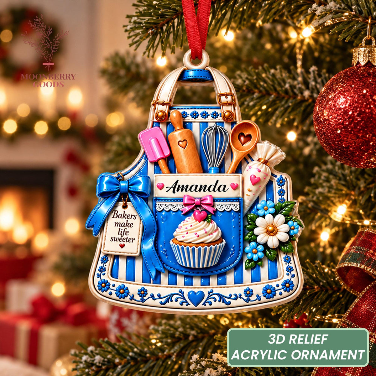 May include: A 3D relief acrylic ornament shaped like a blue and white striped apron. It features a pink spatula, wooden rolling pin, whisk, spoon, and piping bag. A pocket displays the name Amanda, a cupcake, and a tag reading Bakers make life sweeter.