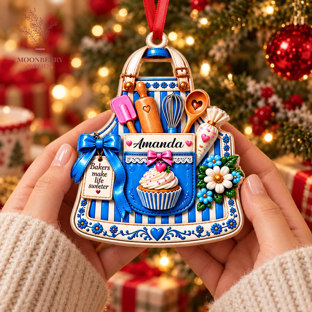 May include: A decorative apron-shaped ornament featuring blue and white vertical stripes, a cupcake graphic, and baking tools including a rolling pin, whisk, and spatula. The text reads Amanda and Bakers make life sweeter with a red ribbon hanger.