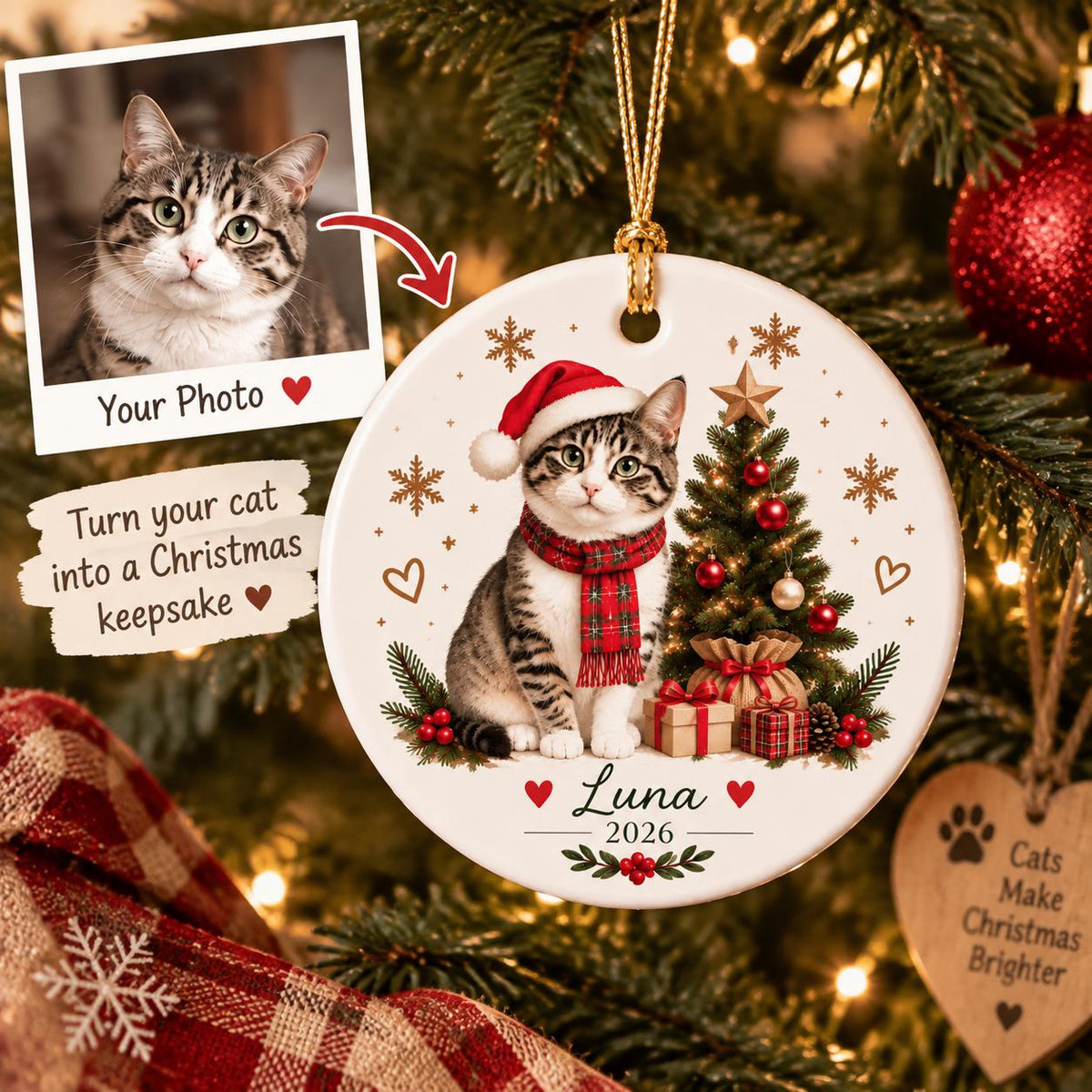 May include: A round white ceramic ornament featuring a tabby cat wearing a red Santa hat and a red plaid scarf. The cat sits beside a decorated Christmas tree with gifts. The text reads Luna and 2026, accented with snowflakes and hearts.