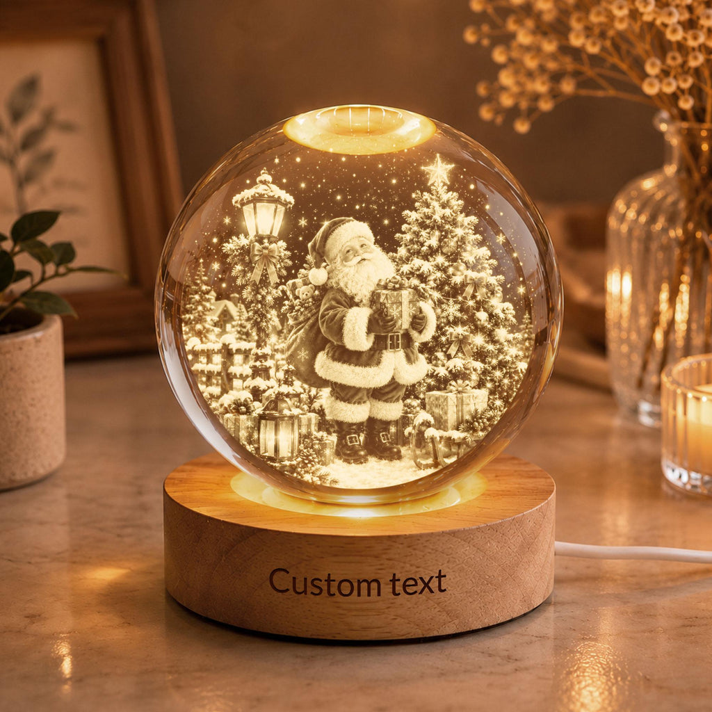 May include: A spherical glass night light featuring an internal 3D laser-etched scene of Santa Claus holding a gift near a decorated Christmas tree and a street lamp. The glass sphere rests on a circular wooden base with the text Custom text.
