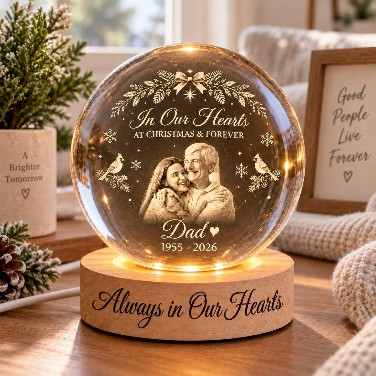May include: A spherical glass ornament on a round wooden base with internal LED lighting. The glass features an etched portrait of two people, the text "In Our Hearts AT CHRISTMAS & FOREVER", "Dad", "1955 - 2026", and cardinal bird motifs. The base reads "Always in Our Hearts".