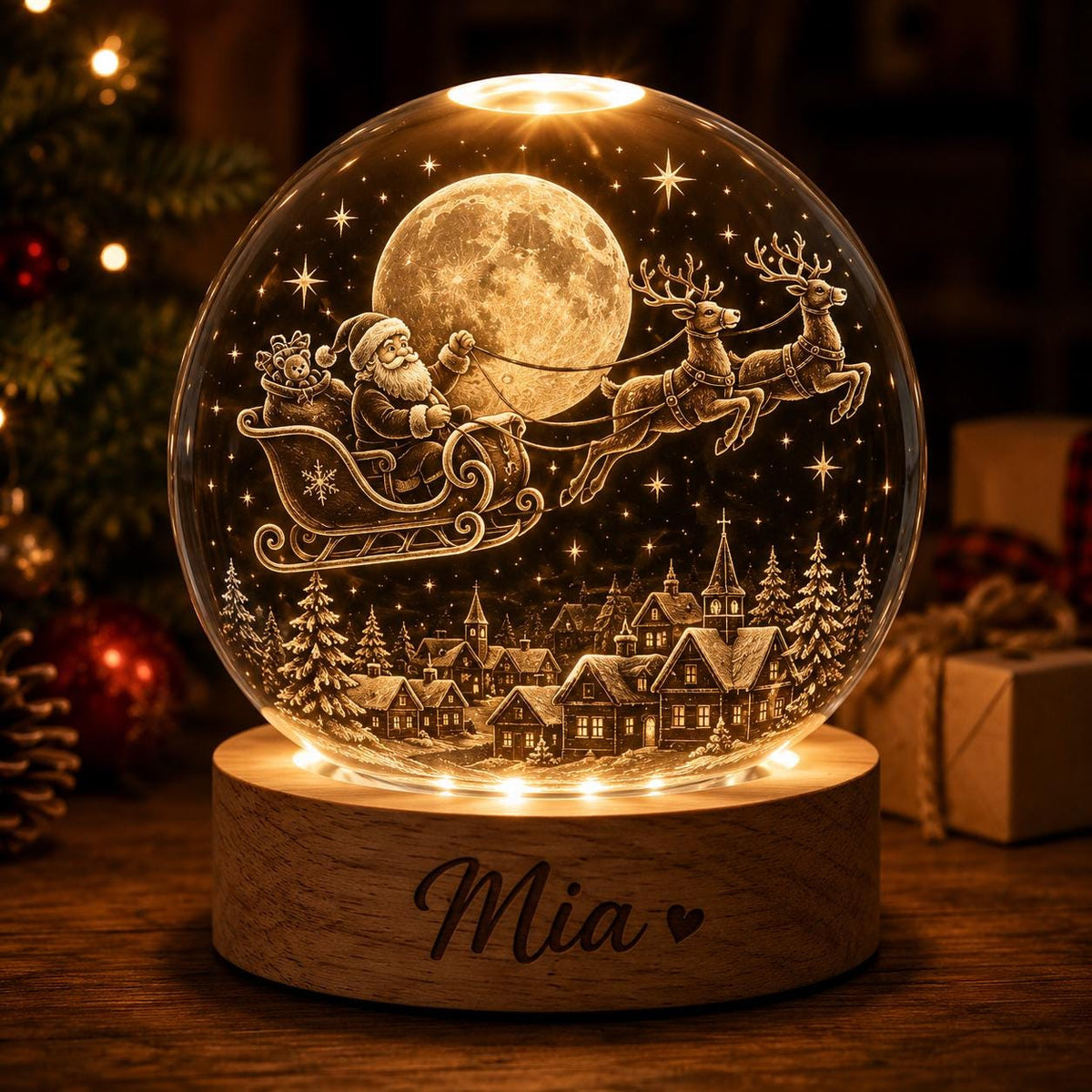 May include: A spherical glass night light featuring an internal 3D laser-etched scene of Santa Claus in a sleigh pulled by reindeer flying over a village under a full moon. The light sits on a round wooden base engraved with the name Mia and a heart.