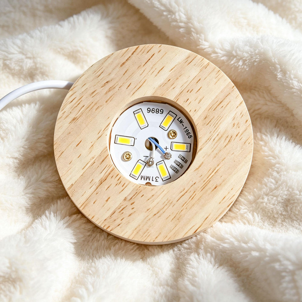 May include: A circular light wood base featuring a central recessed white LED circuit board with six yellow light diodes. The board displays the text 9689, LW-1986, and 31MM. A white power cord extends from the side of the wooden fixture.