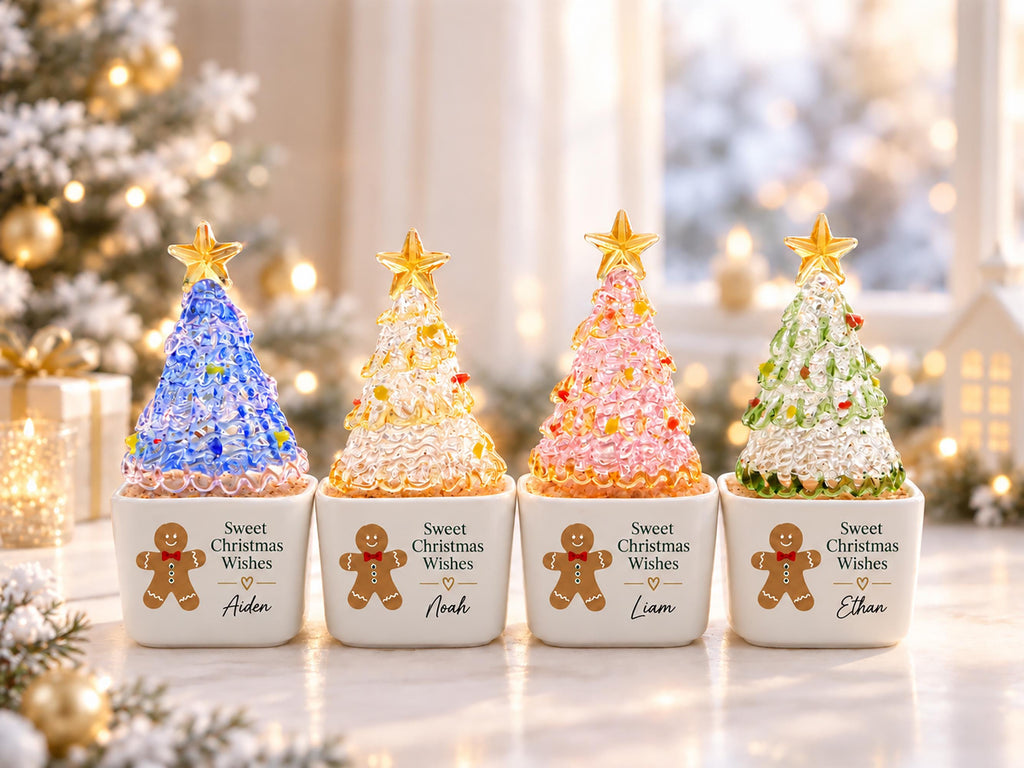 May include: Four white square ceramic planters, each featuring a gingerbread man graphic, the text Sweet Christmas Wishes, and a unique name: Aiden, Noah, Liam, or Ethan. Each planter holds a textured, conical glass tree topped with a gold star.