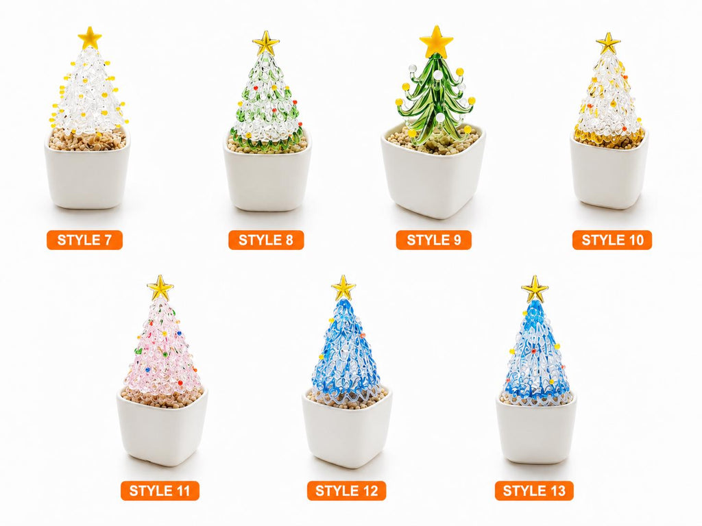 May include: Seven miniature glass Christmas tree figurines in white square pots, labeled Style 7 through Style 13. Each tree features a gold star topper and colorful glass accents, set in a base of small tan pebbles within the white ceramic containers.