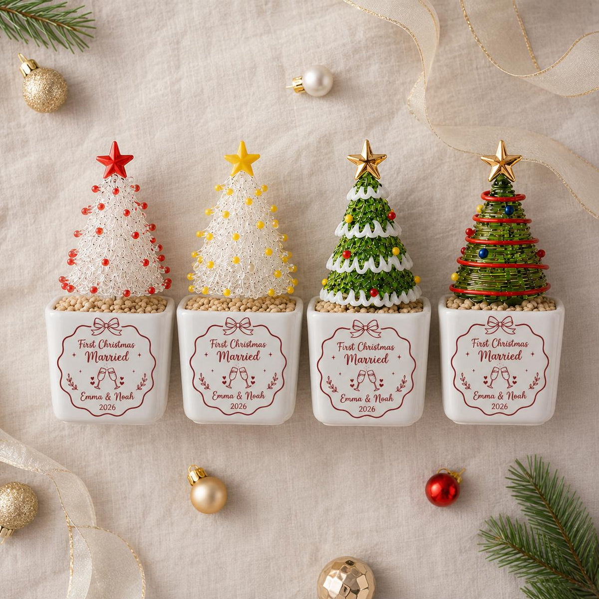 May include: Four miniature Christmas tree ornaments in white square ceramic planters. Each planter features the text First Christmas Married, Emma & Noah, and 2026. The trees are decorated with colorful beads, wire, and a star topper.