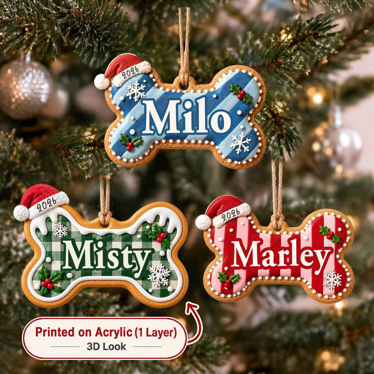 May include: Three bone-shaped Christmas ornaments hanging from twine. Each features a Santa hat with 2026, white icing edges, holly, and snowflakes. The blue, green, and red striped bones are personalized with the names Milo, Misty, and Marley.