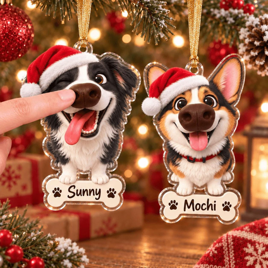 May include: Two acrylic Christmas ornaments shaped like dog heads wearing red Santa hats. One ornament features a black and white dog with the name Sunny on a bone-shaped tag. The other shows a tricolor Corgi with the name Mochi on a bone tag.