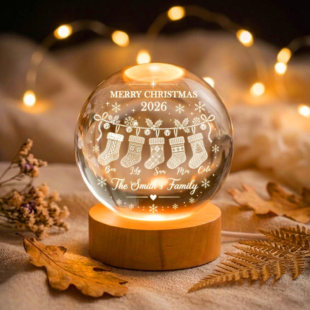 May include: A clear glass sphere lamp on a round wooden base, engraved with "MERRY CHRISTMAS 2026", five hanging stockings, and the names "Ben", "Lily", "Sam", "Mia", "Cole", plus "The Smith's Family" text, illuminated from below.