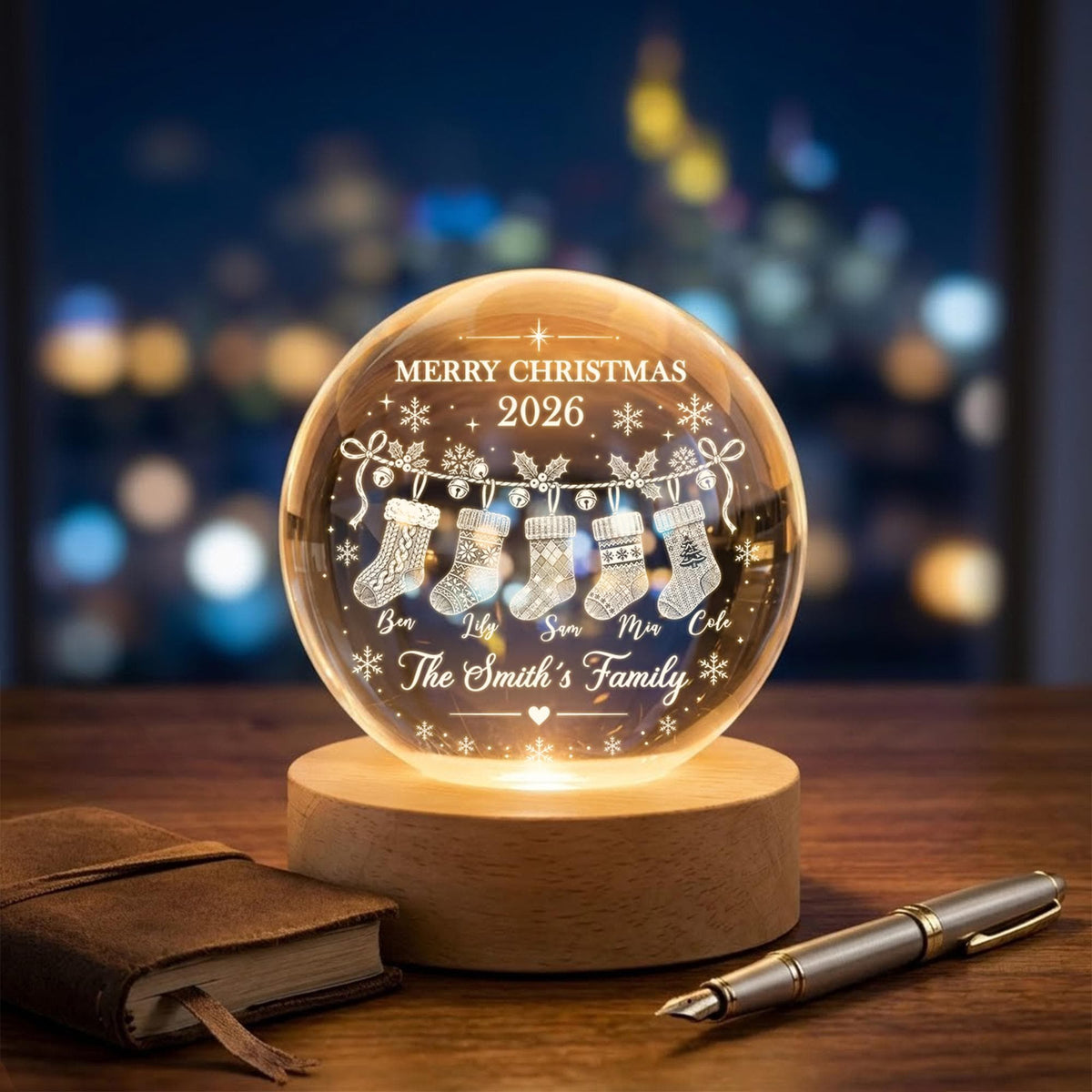 May include: A clear glass sphere lamp on a round wooden base, engraved with MERRY CHRISTMAS 2026, five hanging stockings, and the names Ben, Lily, Sam, Mia, Cole, and The Smith's Family, illuminated from below with a warm light.