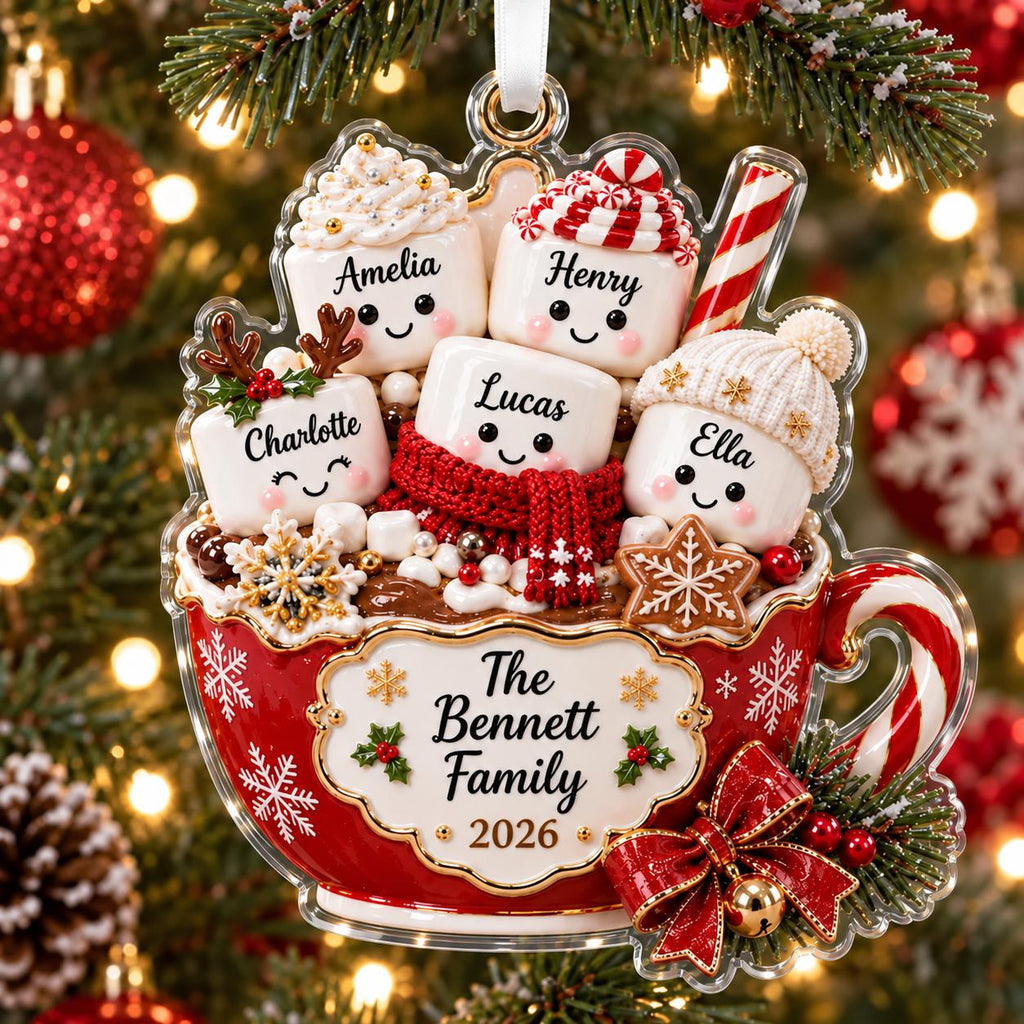 May include: A red Christmas ornament shaped like a mug filled with five smiling marshmallow characters labeled Amelia, Henry, Charlotte, Lucas, and Ella. The mug features the text The Bennett Family 2026, decorated with snowflakes, holly, and a red bow.
