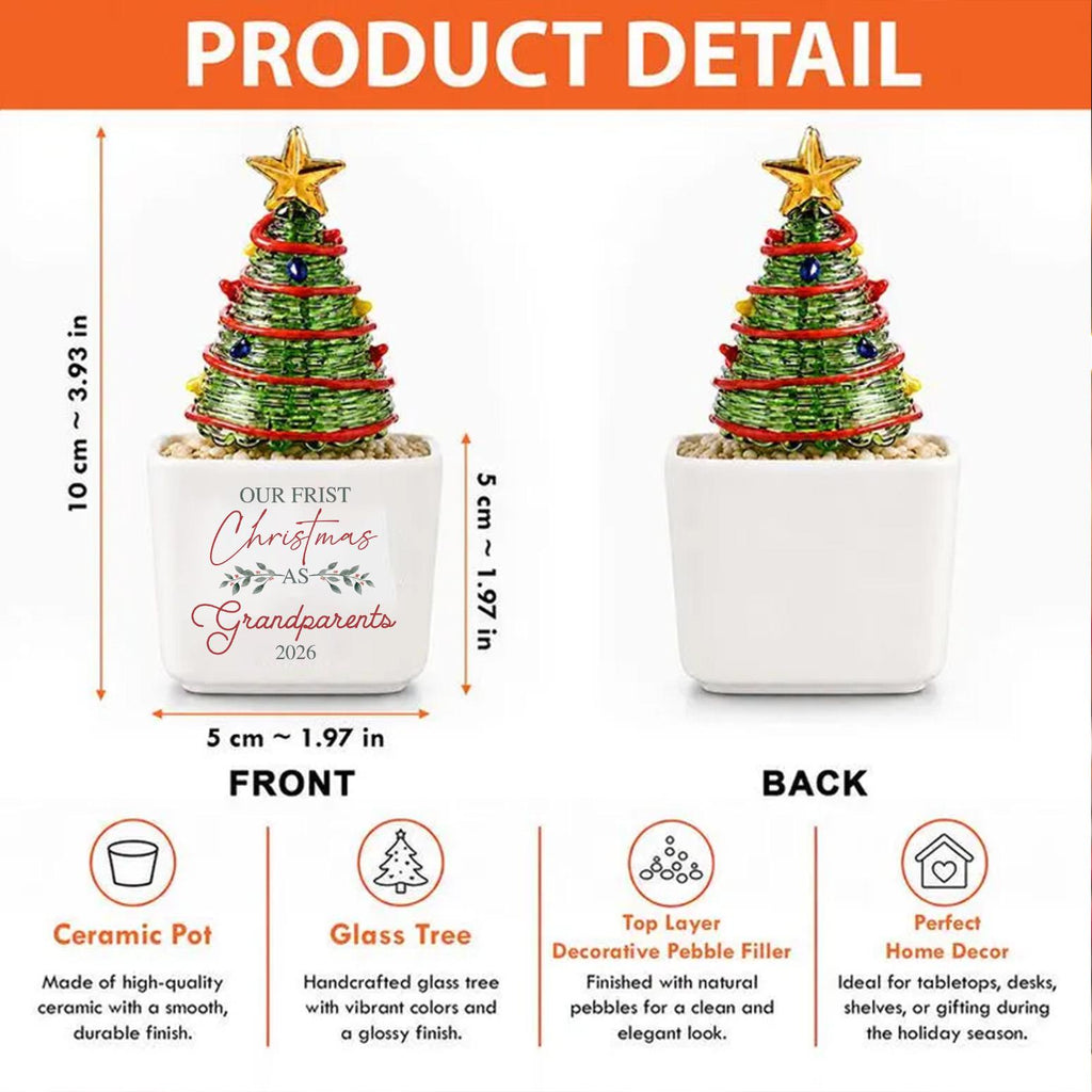 May include: A decorative glass Christmas tree with a gold star topper, red garland, and colorful ornaments, set in a white ceramic pot. The pot features the text "OUR FRIST Christmas AS Grandparents 2026" and measures 10 cm by 5 cm.