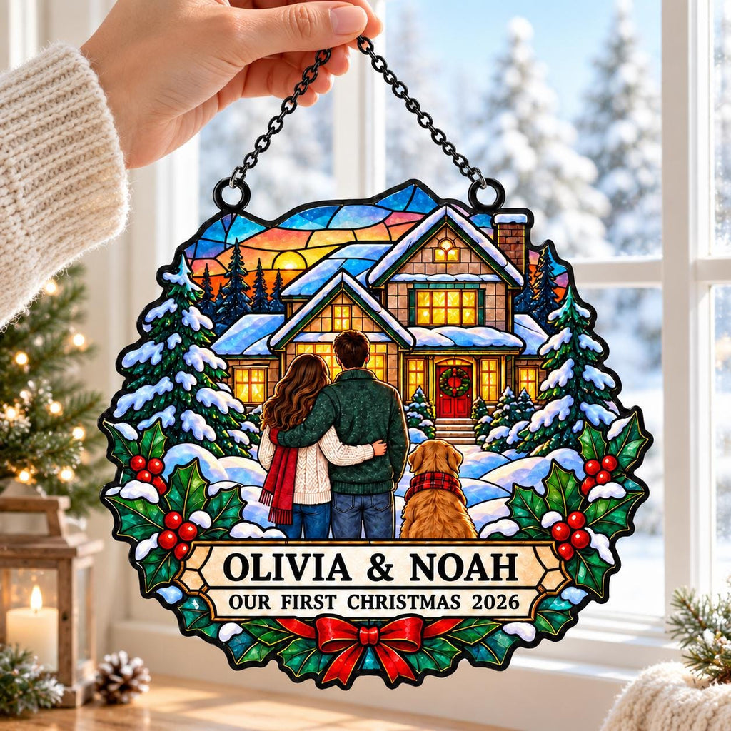 May include: A circular stained glass ornament featuring a couple and a dog standing before a house in a snowy landscape. The text reads OLIVIA & NOAH OUR FIRST CHRISTMAS 2026. The design includes pine trees, holly leaves, red berries, and a red bow.