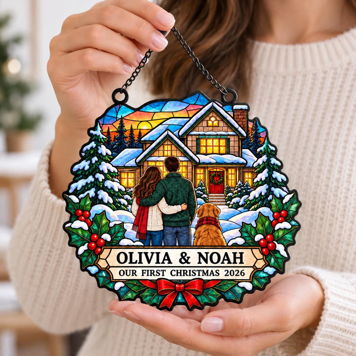 May include: A circular stained glass style ornament featuring a winter house scene with two people and a dog. The text reads OLIVIA & NOAH and OUR FIRST CHRISTMAS 2026. The design includes snow-covered pine trees, holly leaves, red berries, and a red bow at the bottom, suspended by a black chain.