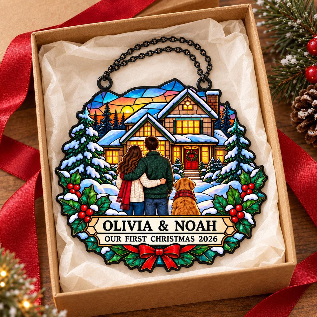 May include: A circular hanging ornament featuring a stained-glass style illustration of a couple and a dog standing before a snow-covered house. The text reads OLIVIA & NOAH OUR FIRST CHRISTMAS 2026. It is framed by holly leaves and a red bow.