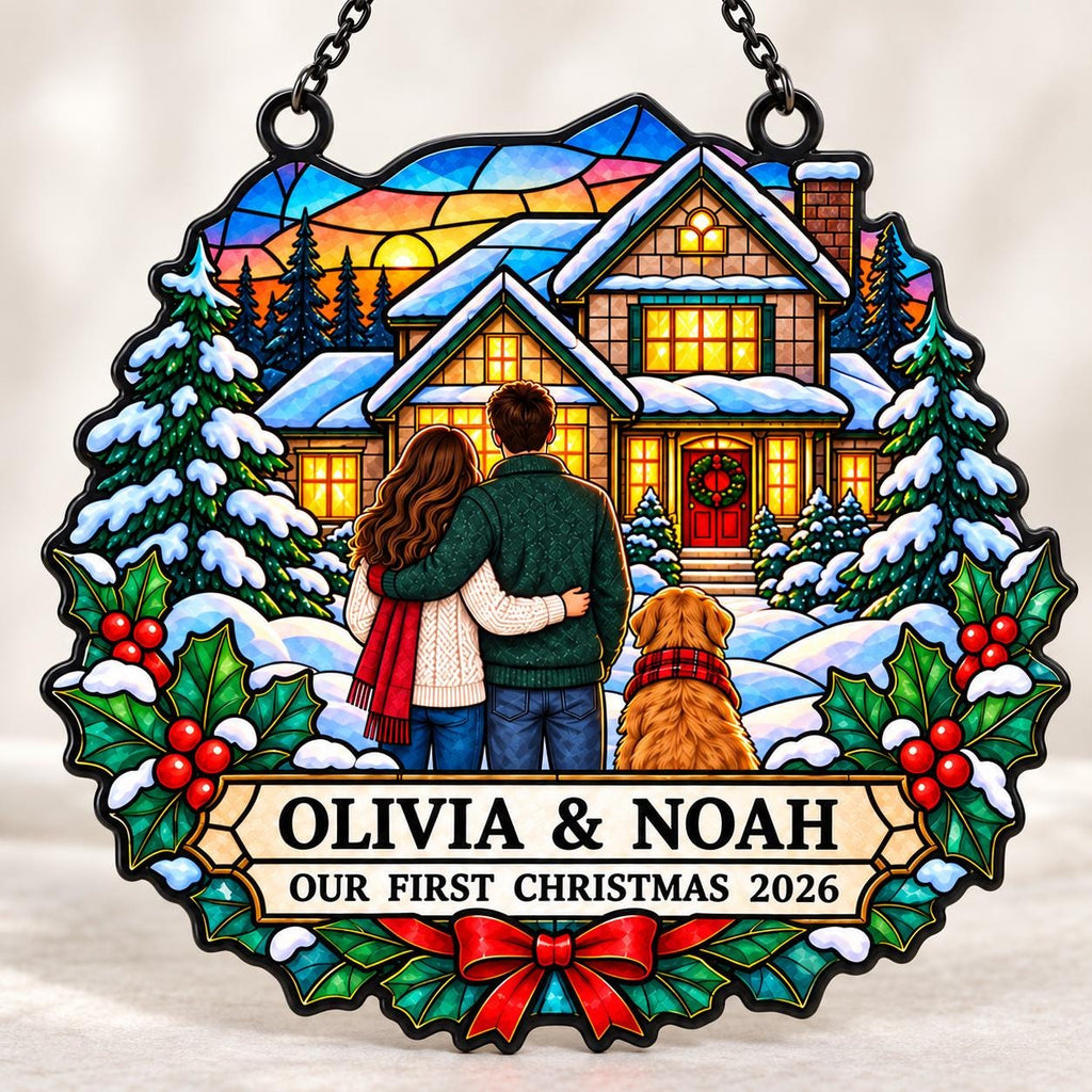 May include: A circular stained-glass style hanging ornament featuring a couple and a dog standing before a snow-covered house at sunset. The text reads OLIVIA & NOAH OUR FIRST CHRISTMAS 2026. The design includes pine trees, holly leaves, and a red bow.