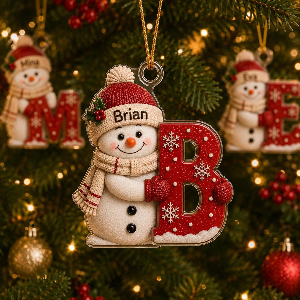 May include: A clear acrylic Christmas ornament featuring a white snowman wearing a red knit hat and a beige scarf. The snowman holds a large, red, glittery letter B decorated with white snowflakes. The name Brian is printed on the hat.