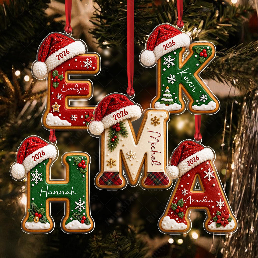 May include: Five hanging letter ornaments shaped like gingerbread cookies, each wearing a red Santa hat with the year 2026. The letters E, K, H, M, and A feature festive decorations like holly, snowflakes, and names including Evelyn, Kevin, Hannah, Michel, and Amelia.