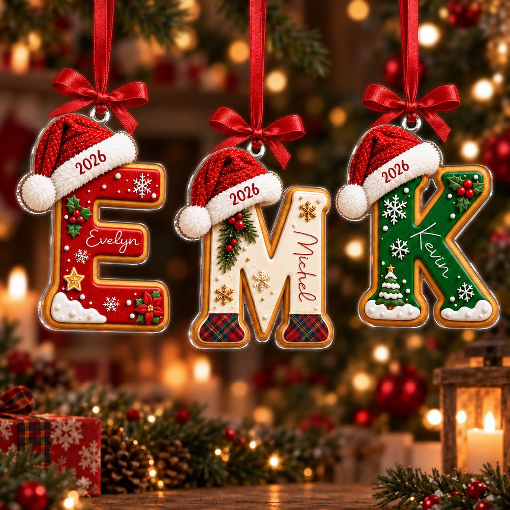 May include: Three hanging Christmas ornaments shaped like the letters E, M, and K. Each letter features a red Santa hat with the year 2026, personalized names Evelyn, Michel, and Kevin, and festive decorations like snowflakes, holly, and trees.
