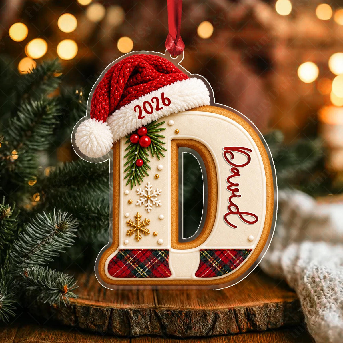 May include: A clear acrylic Christmas ornament shaped like the letter D, featuring a red Santa hat with the year 2026, a sprig of holly, white and gold snowflakes, and red and green plaid accents. The name David is printed in red script on the side.
