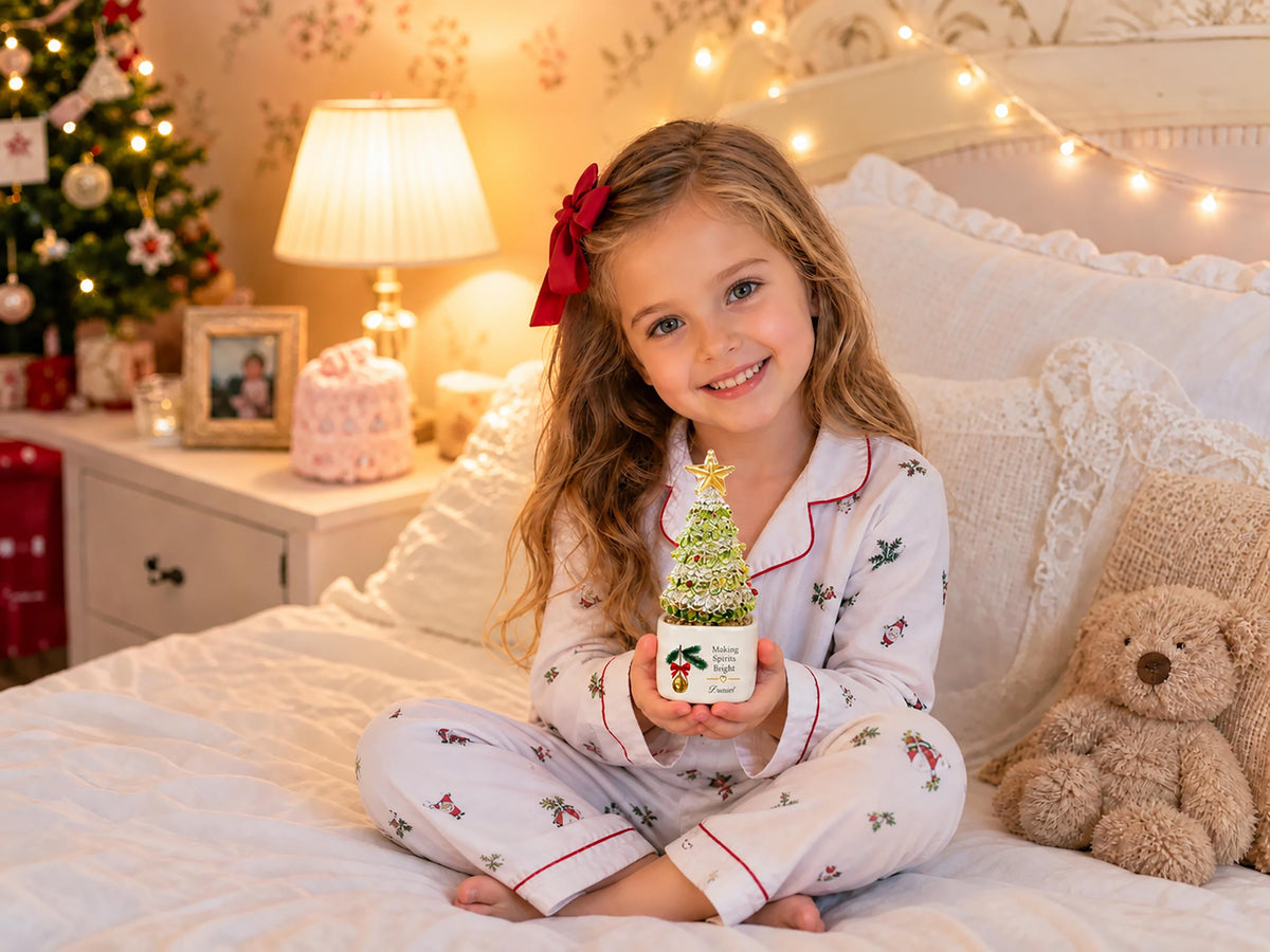 May include: A small, conical, green and silver textured Christmas tree ornament with a gold star topper, set on a white square base featuring a graphic of holly berries and the text "Making Spirits Bright" in black lettering.