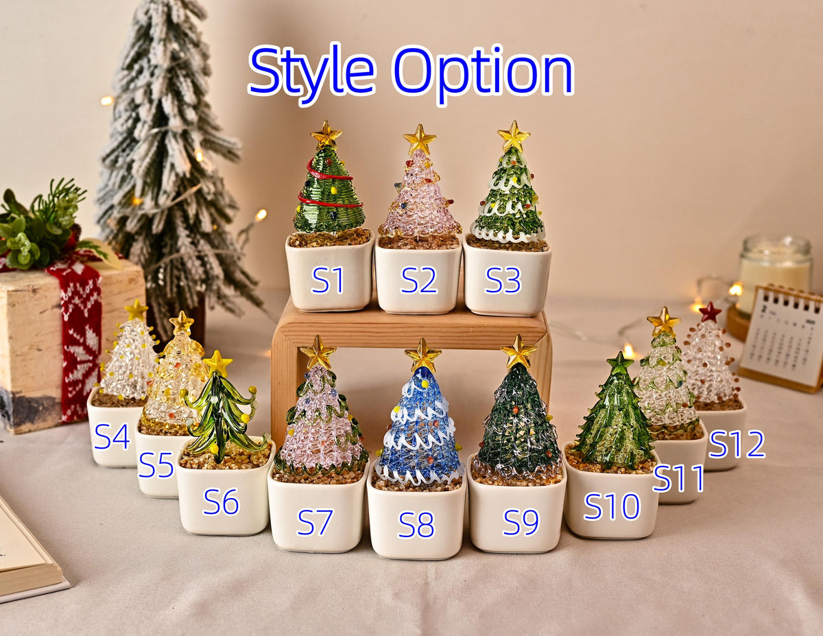 May include: A collection of twelve miniature glass Christmas tree figurines, labeled S1 through S12, each featuring a gold star topper and a white square pot filled with small pebbles. The trees vary in color, including green, blue, pink, and clear.