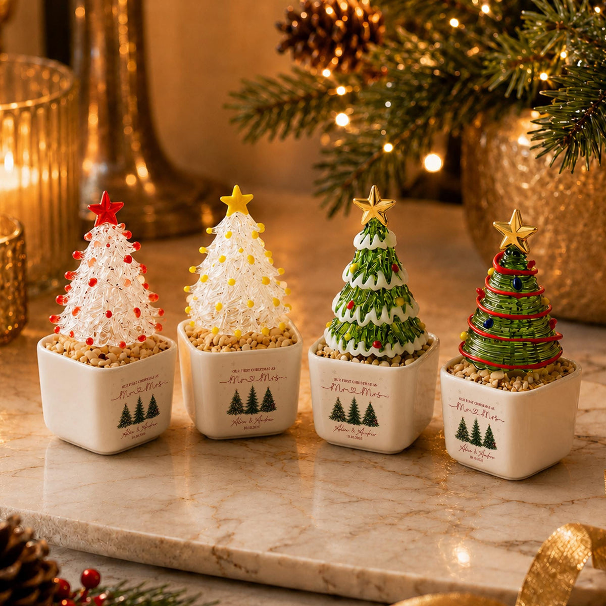 May include: Four miniature glass Christmas tree figurines in square white ceramic pots. Each tree features a gold or red star topper and sits on a base of small pebbles. The pots are printed with the text "Our First Christmas as Mr & Mrs".