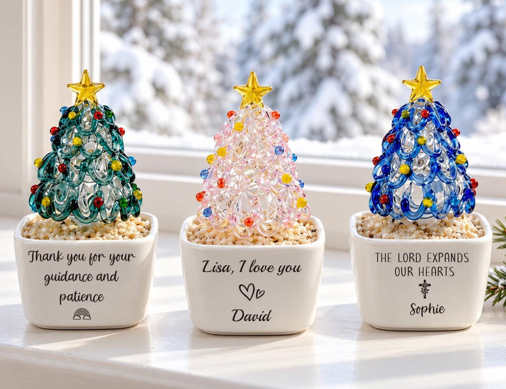 May include: Three glass Christmas tree figurines in white square ceramic pots filled with small pebbles. The left pot reads Thank you for your guidance and patience with a rainbow. The center reads Lisa, I love you with a heart and David. The right reads THE LORD EXPANDS OUR HEARTS with a cross and Sophie.