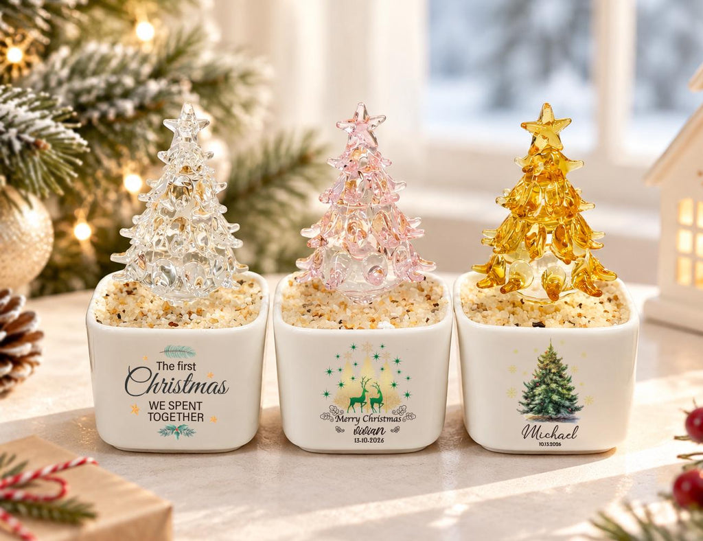 May include: Three square white ceramic planters containing small glass Christmas trees in clear, pink, and gold. The planters feature printed text and graphics: The first Christmas WE SPENT TOGETHER, Merry Christmas Lilian 12.10.2024, and Michael 12.10.2024.