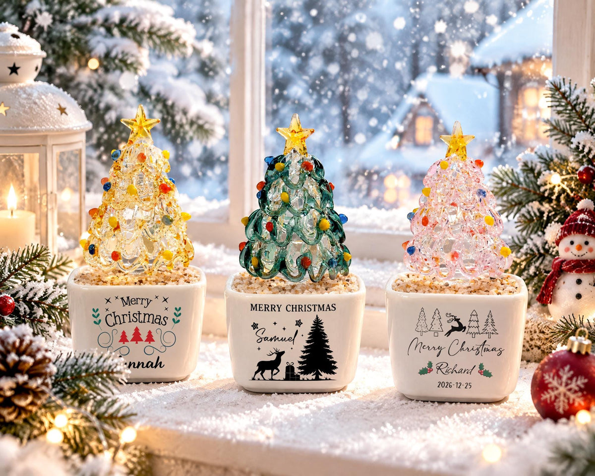 May include: Three glass Christmas tree ornaments in square white ceramic pots. The left pot says Merry Christmas and Hannah. The center pot says Merry Christmas, Samuel, and features a tree and deer. The right pot says Merry Christmas, Richard, 2026-12-25.